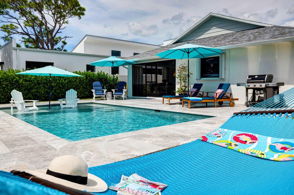 Pool and patio with hammock, grill, lounge chairs and umbrellas
